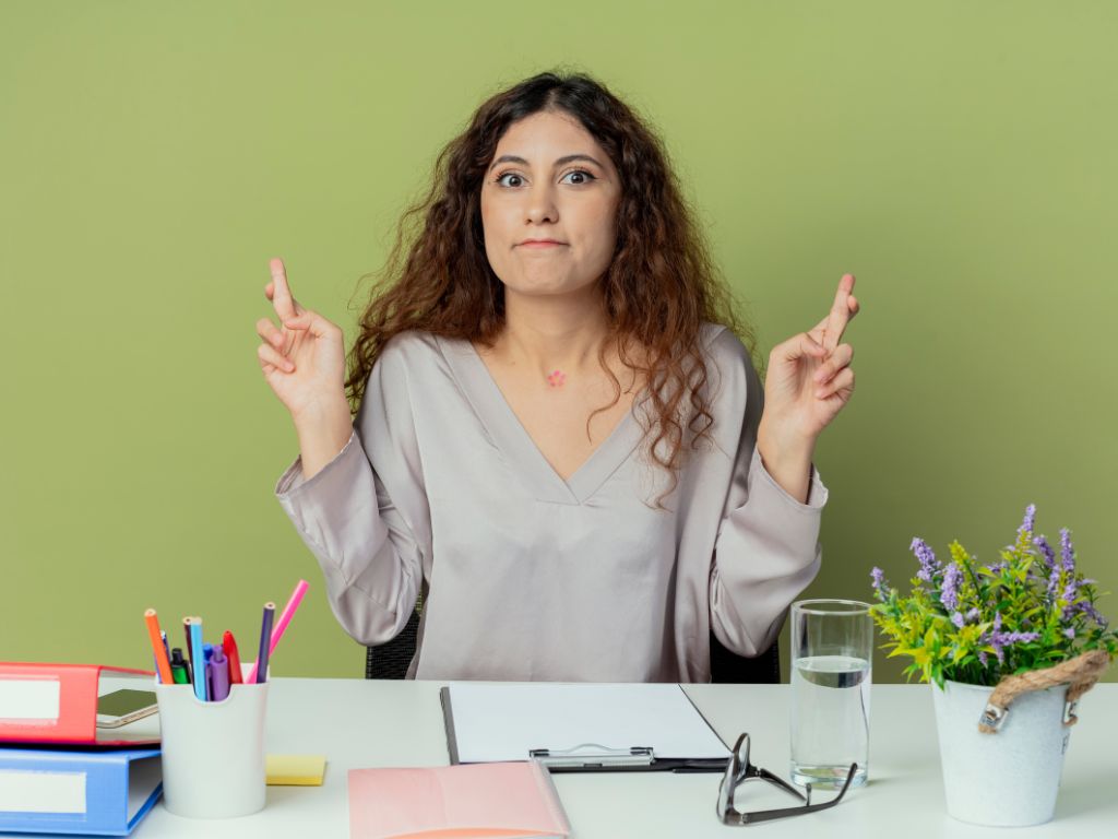 worried girl in front of the green background with crossed fingers